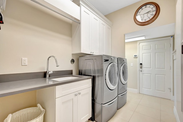 laundry area featuring cabinet space, a sink, baseboards, light tile patterned flooring, and washer and dryer