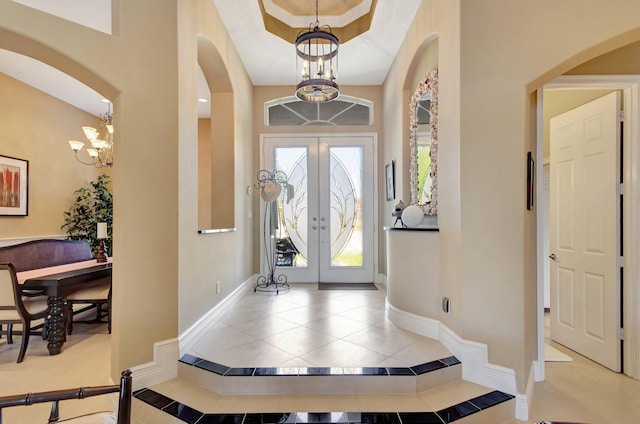 foyer with tile patterned flooring, arched walkways, baseboards, and a chandelier