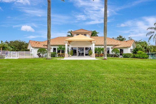 back of house featuring a lawn, fence, and stucco siding