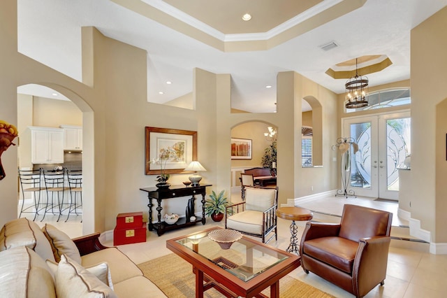 interior space with a raised ceiling, arched walkways, french doors, recessed lighting, and light tile patterned floors