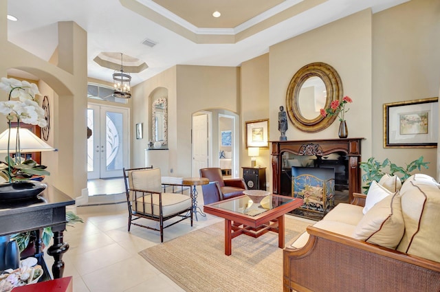 living area with french doors, visible vents, arched walkways, a raised ceiling, and ornamental molding