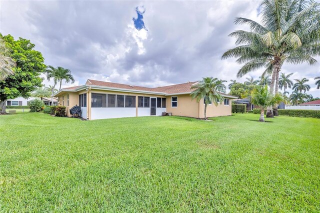 4160 Juniper Ter, Boynton Beach, FL 33436 - back of house featuring a lawn, a sunroom, and stucco siding