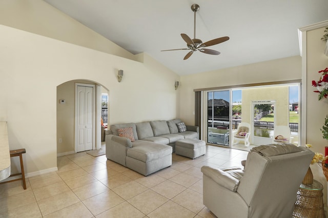 living room with high vaulted ceiling, light tile patterned flooring, ceiling fan, arched walkways, and baseboards