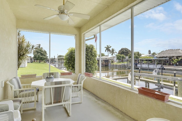 sunroom / solarium featuring a water view, finished concrete flooring, ceiling fan, and a healthy amount of sunlight