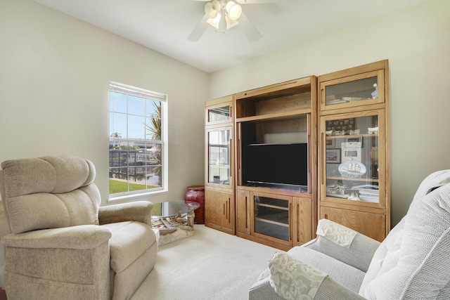 carpeted living area with a ceiling fan