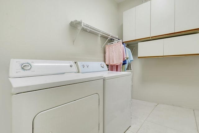 laundry room featuring washer and clothes dryer, light tile patterned floors, and cabinet space