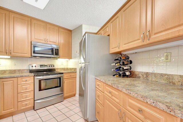 3718 Victoria Dr, West Palm Beach, FL 33406 - kitchen featuring stainless steel appliances, light brown cabinetry, tasteful backsplash, and a textured ceiling