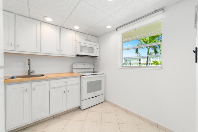 kitchen featuring white cabinets, a sink, white appliances, light countertops, and a paneled ceiling