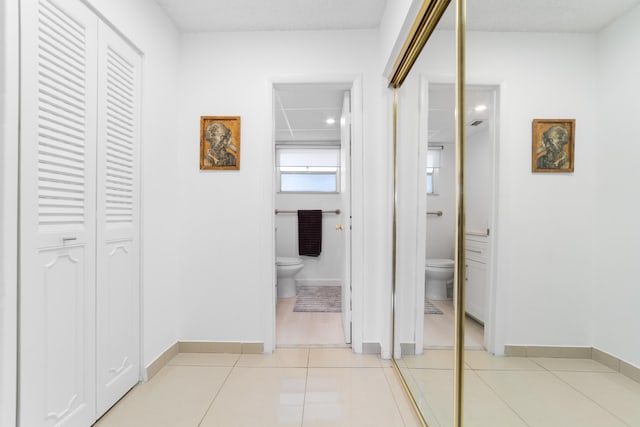 hall featuring baseboards and light tile patterned floors