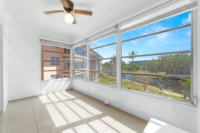 unfurnished sunroom with a water view, ceiling fan, and a wealth of natural light