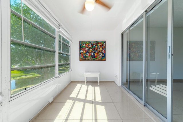 unfurnished sunroom featuring tile patterned floors, baseboards, and a ceiling fan