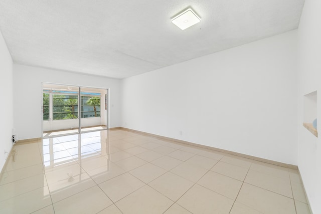 empty room featuring baseboards and light tile patterned flooring