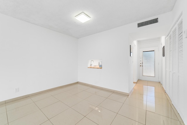 unfurnished room with light tile patterned flooring, baseboards, and visible vents