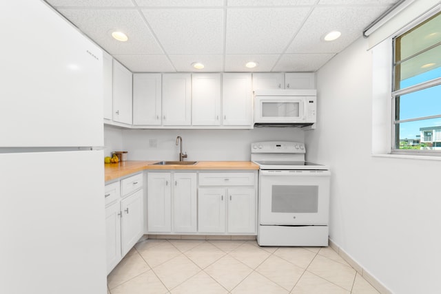 kitchen with a sink, white appliances, a paneled ceiling, white cabinetry, and recessed lighting