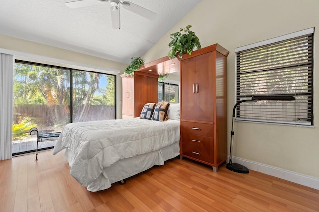 bedroom with a textured ceiling, access to outside, vaulted ceiling, and wood finished floors