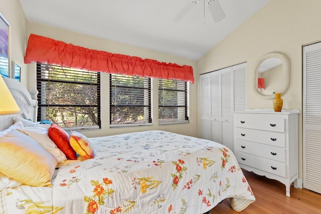bedroom with multiple closets, a ceiling fan, wood finished floors, and lofted ceiling