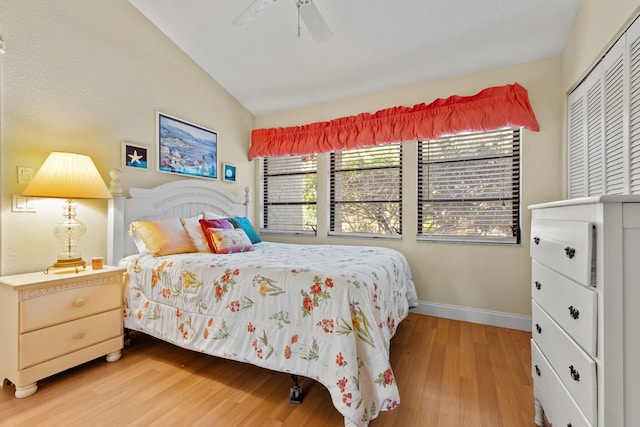 bedroom with baseboards, vaulted ceiling, multiple windows, and light wood finished floors