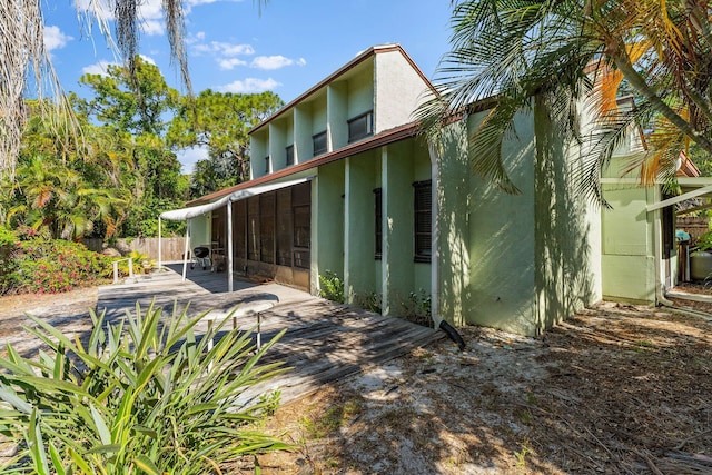 rear view of property with stucco siding and fence