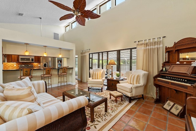 living room featuring tile patterned flooring, ceiling fan, a textured ceiling, and a towering ceiling