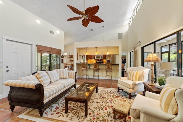 tiled living area with a textured ceiling, a healthy amount of sunlight, ceiling fan, and high vaulted ceiling