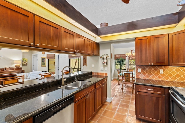 kitchen with decorative backsplash, appliances with stainless steel finishes, a sink, a chandelier, and light tile patterned flooring