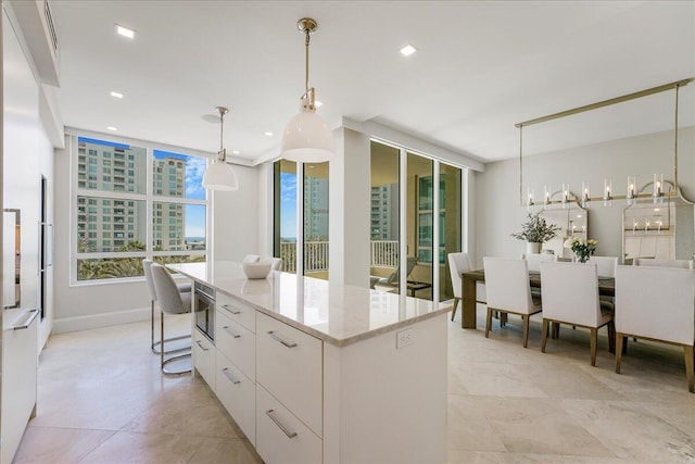 3720 S Ocean Blvd Unit 603, Highland Beach, FL 33487 - kitchen with a center island, light stone counters, hanging light fixtures, modern cabinets, and white cabinetry