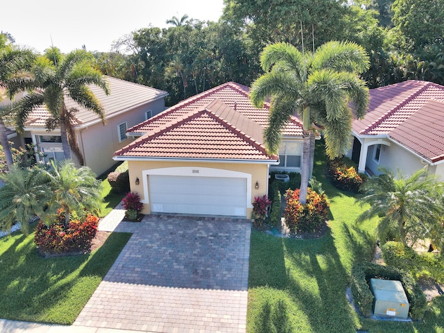 view of front of property with an attached garage, a tile roof, a front lawn, stucco siding, and driveway