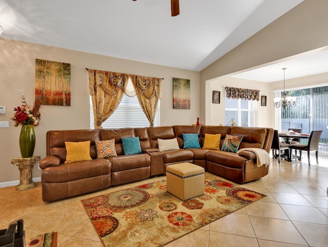 living area with light tile patterned floors, vaulted ceiling, and ceiling fan with notable chandelier