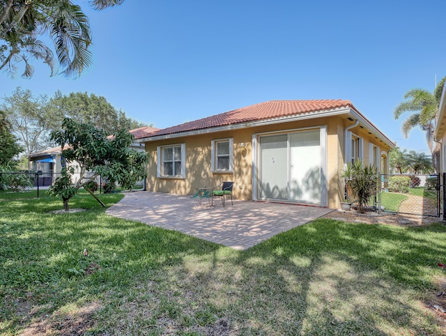 back of property featuring fence, a patio, a yard, and a tile roof