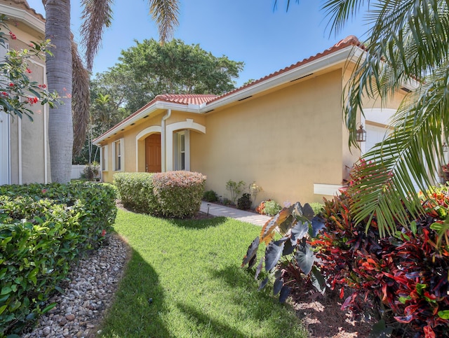view of property exterior featuring a yard, stucco siding, and a tiled roof