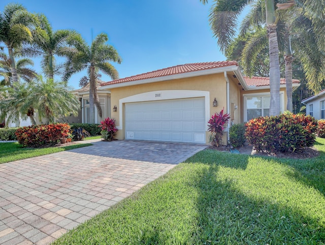 view of front of property with a tiled roof, a garage, decorative driveway, a front lawn, and stucco siding
