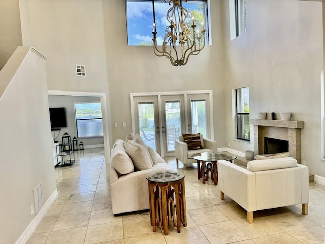 living room with a towering ceiling, french doors, baseboards, and a chandelier