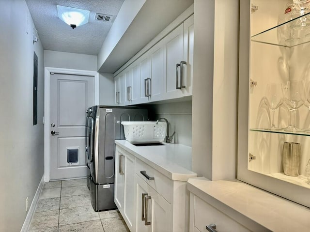 clothes washing area featuring baseboards, a textured ceiling, cabinet space, and washing machine and clothes dryer