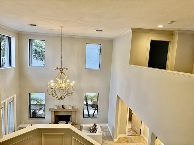 entrance foyer featuring a towering ceiling, a chandelier, a fireplace, baseboards, and ornamental molding