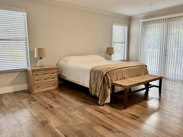 bedroom featuring access to exterior, light wood-style flooring, crown molding, and baseboards