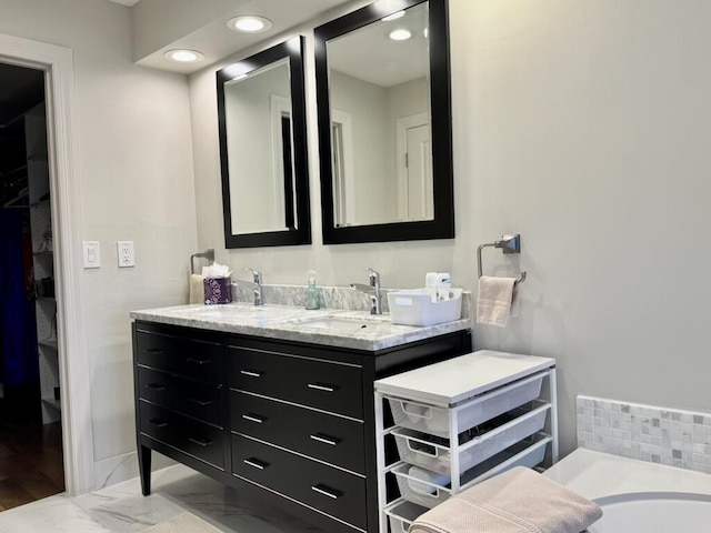 full bath featuring double vanity, a tub, and recessed lighting