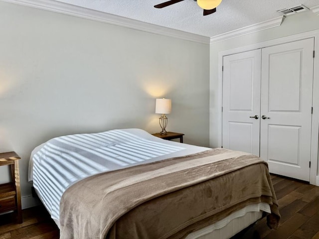 bedroom with dark wood finished floors, ornamental molding, a closet, a textured ceiling, and a ceiling fan