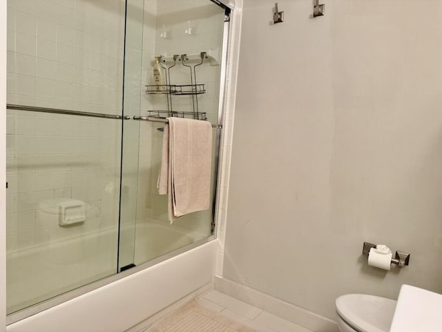 bathroom with tile patterned floors, toilet, enclosed tub / shower combo, and baseboards