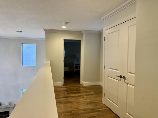 corridor with crown molding, dark wood-type flooring, a textured ceiling, baseboards, and recessed lighting