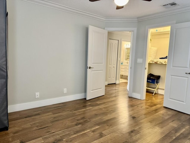 bedroom with ornamental molding, dark wood finished floors, a spacious closet, baseboards, and a closet