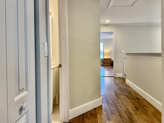 hallway featuring hardwood / wood-style floors, baseboards, and crown molding