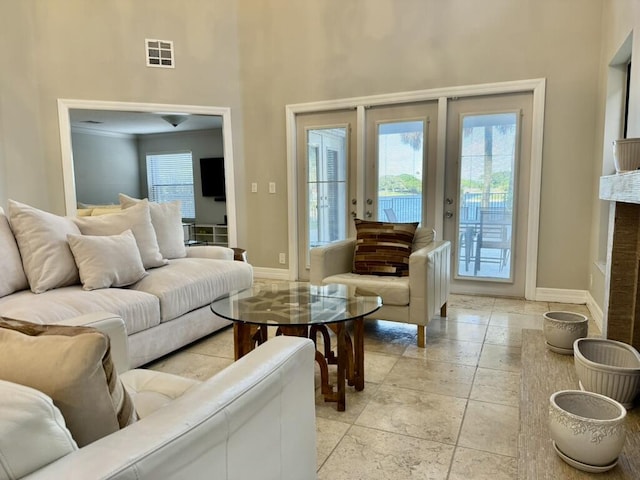 living area with a high ceiling, stone tile floors, baseboards, and ornamental molding