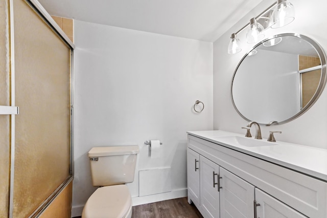 full bathroom featuring wood finished floors, toilet, vanity, and a shower with door