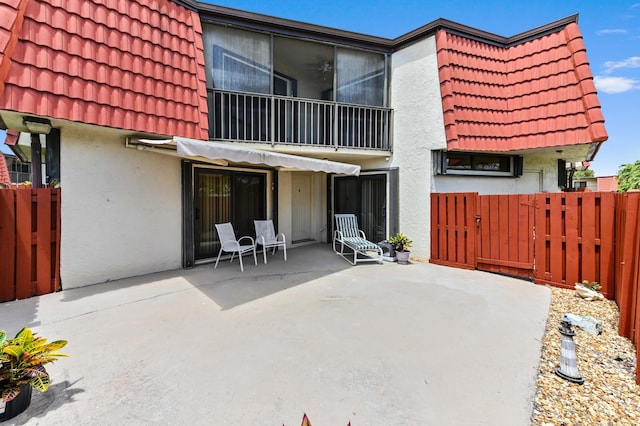 back of house with stucco siding, a tile roof, fence, and a patio area