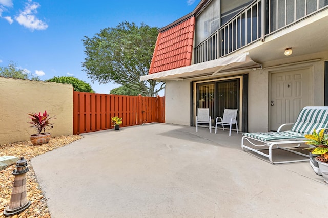 view of patio with fence and a balcony