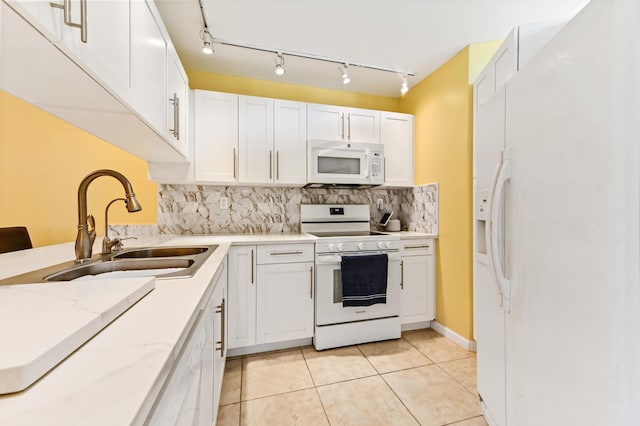 kitchen with white cabinets, a sink, light tile patterned flooring, tasteful backsplash, and white appliances