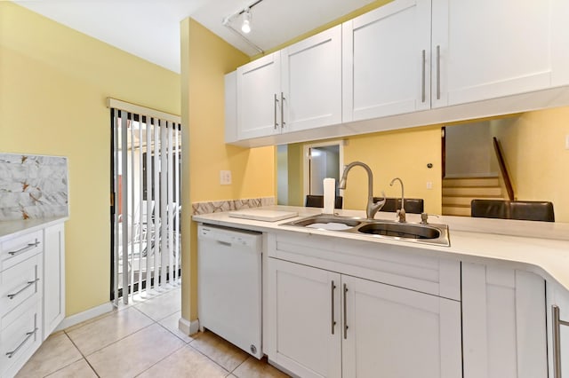 kitchen with light countertops, a sink, white cabinetry, dishwasher, and light tile patterned floors