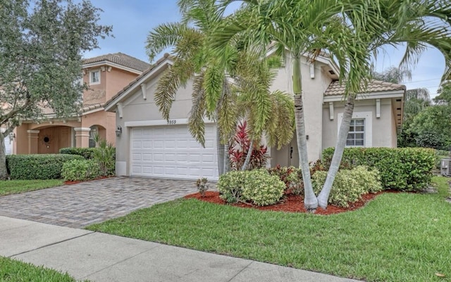 5959 SE Crooked Oak Ave, Hobe Sound, FL 33455 - view of front of house with a front lawn, a tiled roof, a garage, stucco siding, and decorative driveway