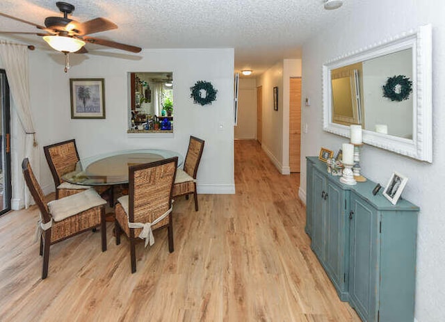 dining space with baseboards, a textured ceiling, light wood-style floors, and ceiling fan