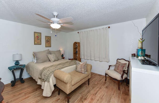 bedroom featuring light wood-type flooring, a textured ceiling, and ceiling fan